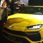 En man står bredvid en Lamborghini Urus. (AI text)