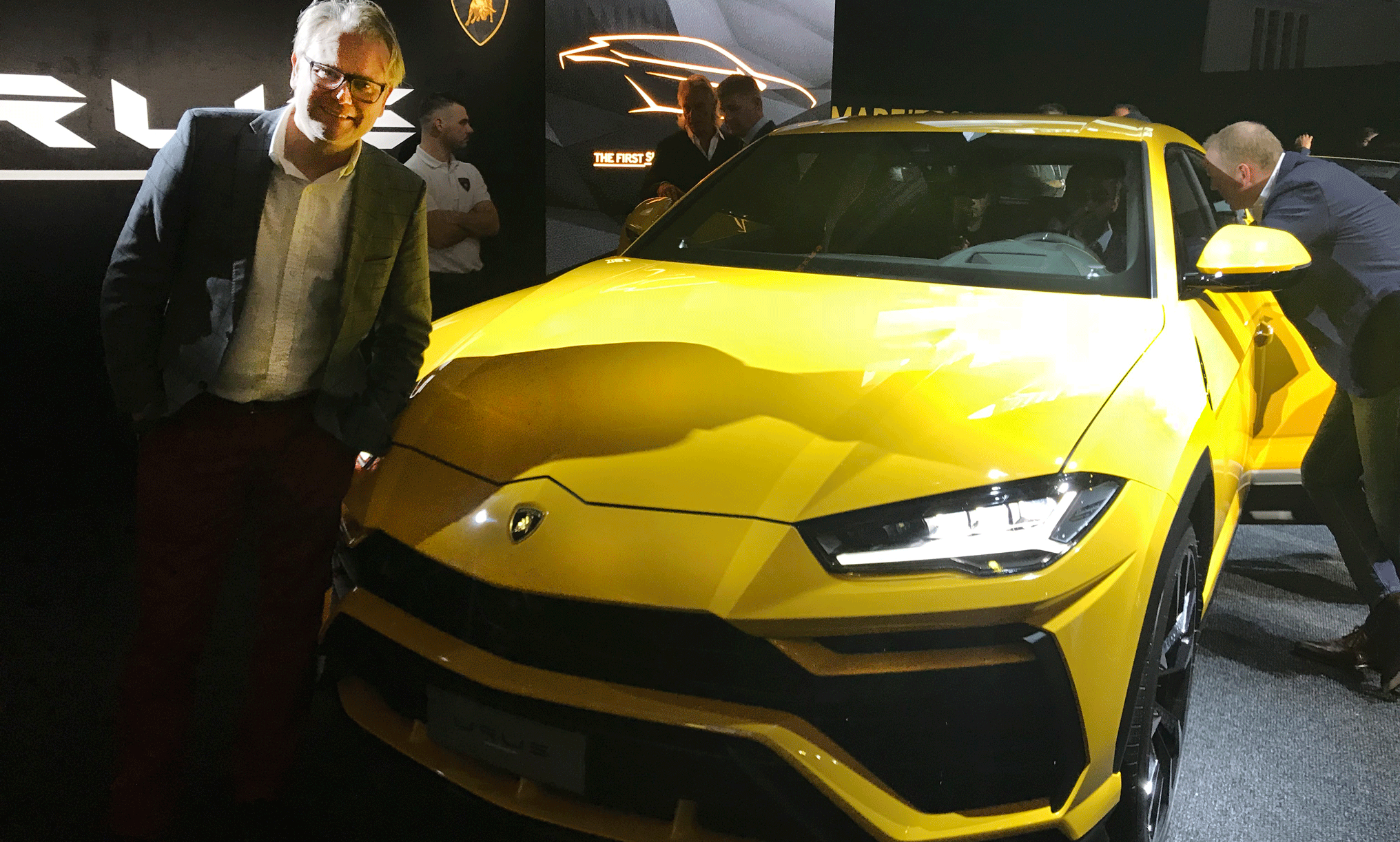 En man står bredvid en Lamborghini Urus. (AI text)