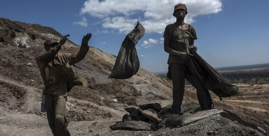 En man står på en backe med en spade. (AI text)