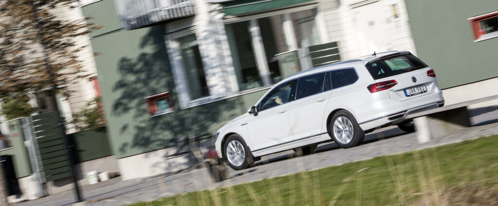 En vit bil kör nerför en gata. (AI text)