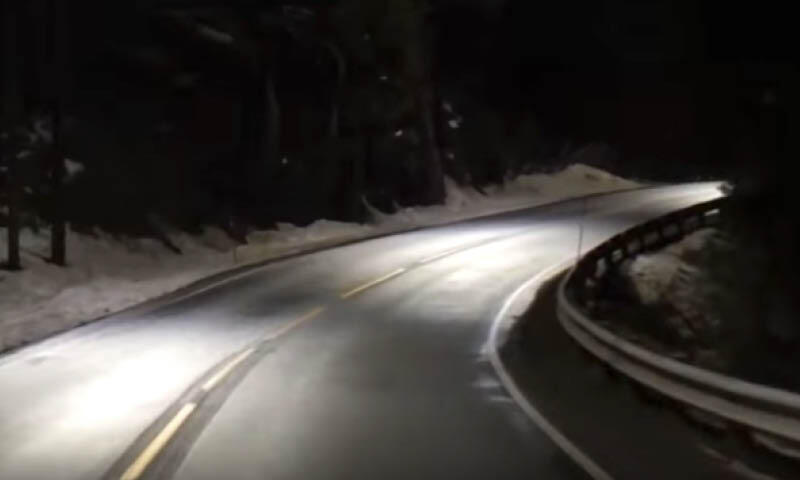 En bil kör nerför en bergsväg på natten. (AI text)