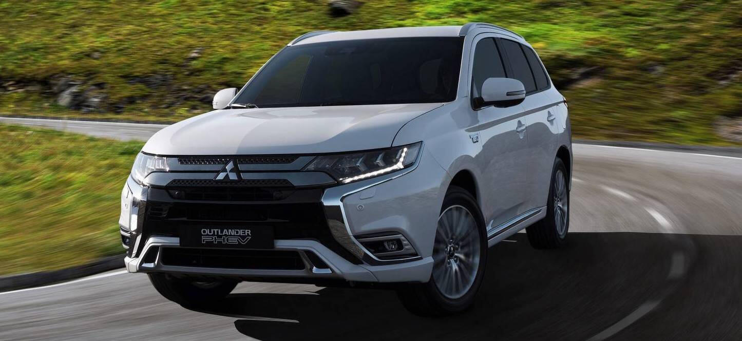 En vit 2019 Mitsubishi Outlander SUV kör längs en krökt väg. (AI text)