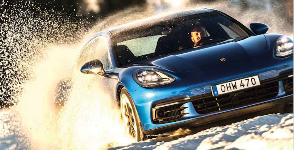 En blå Porsche Panamera GTS kör genom snön. (AI text)