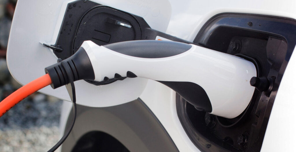 En vit bil är uppkopplad till en elladdare. (AI text)