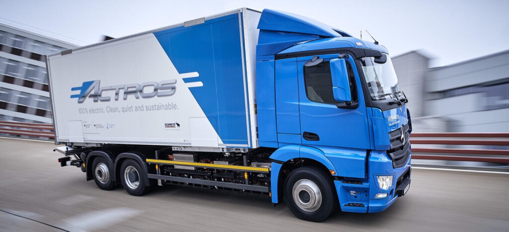 En blå och vit lastbil kör nerför en väg. (AI text)