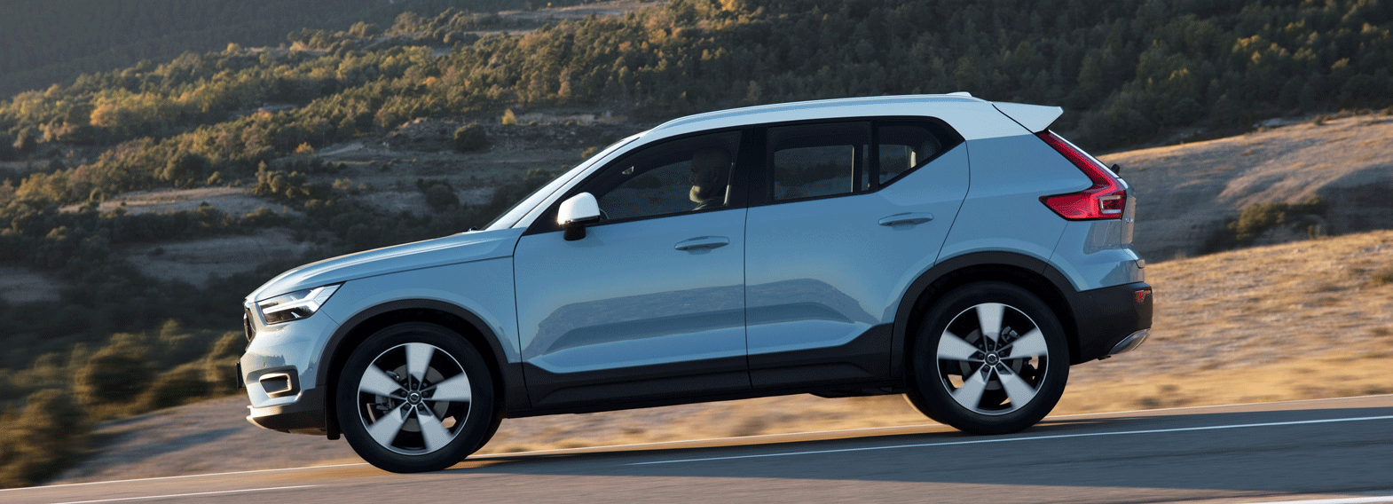 En Volvo XC90 SUV kör nerför en bergsväg. (AI text)