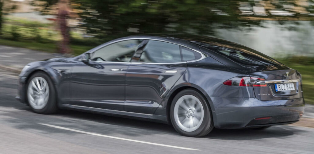 En Tesla Model S kör nerför en landsväg. (AI text)