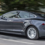 En Tesla Model S kör nerför en landsväg. (AI text)