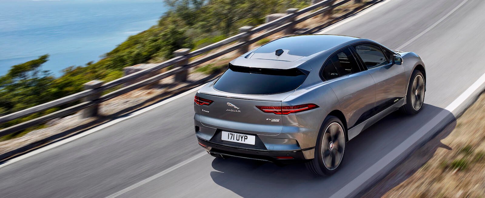 Den nya Jaguar I-Pace kör nedför en bergväg. (AI text)
