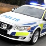 En polisbil kör längs en väg. (AI text)