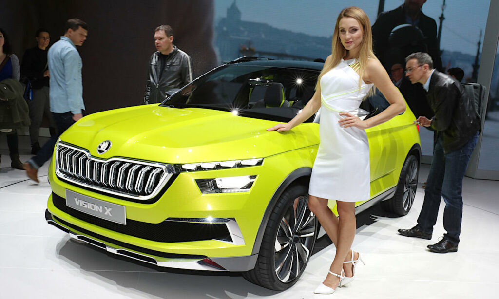 En kvinna står bredvid en grön Skoda SUV på Detroit Motorshow. (AI text)