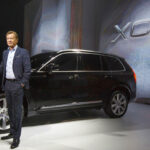 En man står bredvid en Volvo XC90 SUV på Shanghais bilsalong. (AI text)