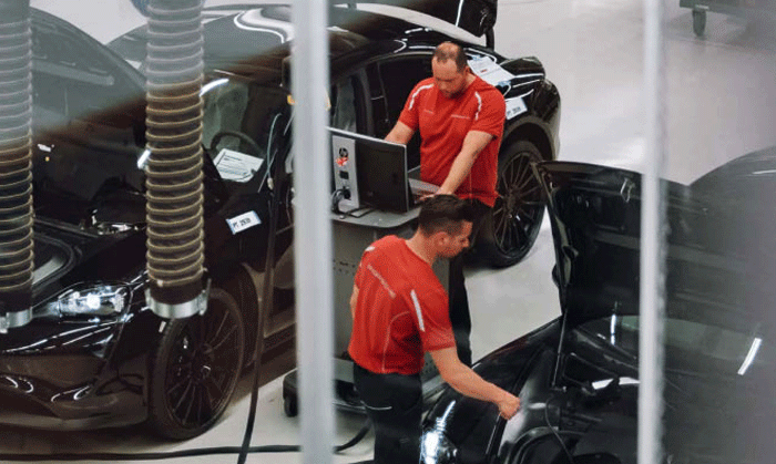 En man arbetar med en bil i en fabrik. (AI text)