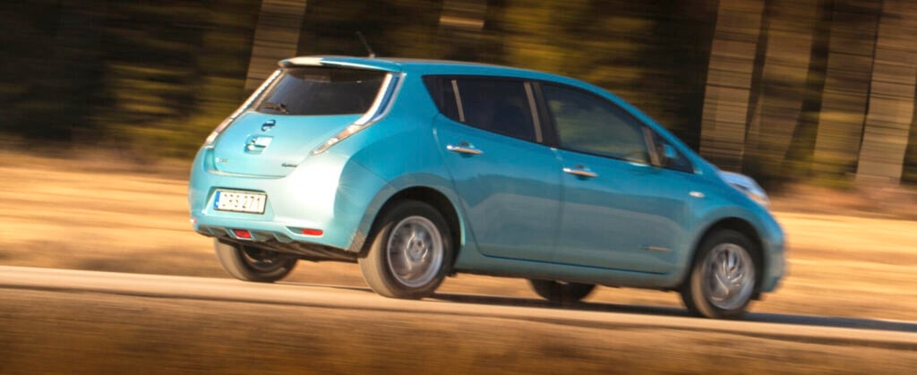 En blå Nissan Leaf kör längs en landsväg. (AI text)