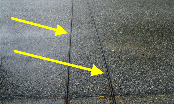 En bil står parkerad på en gata med ett gult piltecken som pekar åt höger. (AI text)