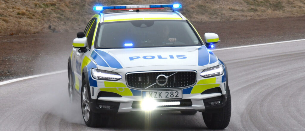 En polisbil kör längs en väg. (AI text)