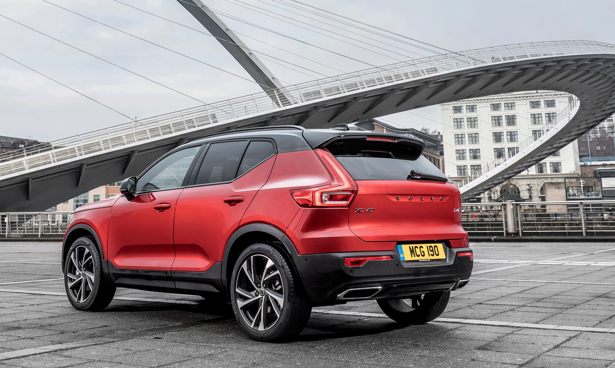 Volvo XC90 står parkerad framför en bro. (AI text)