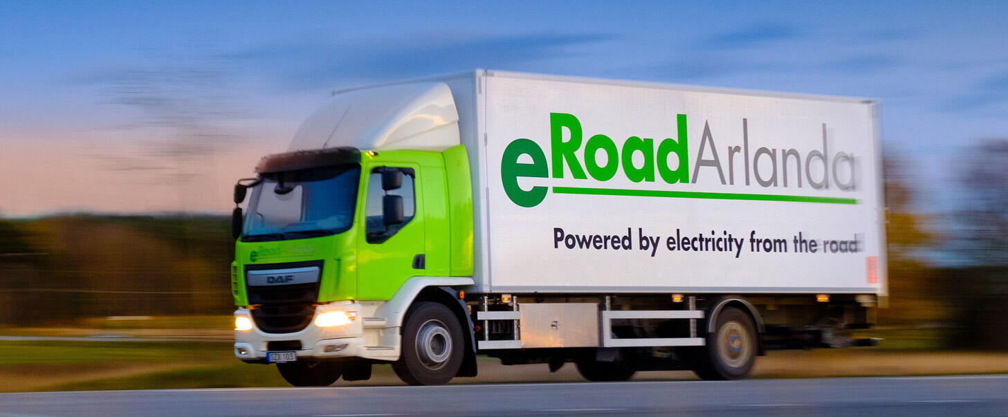 En grön lastbil kör ner vägen. (AI text)