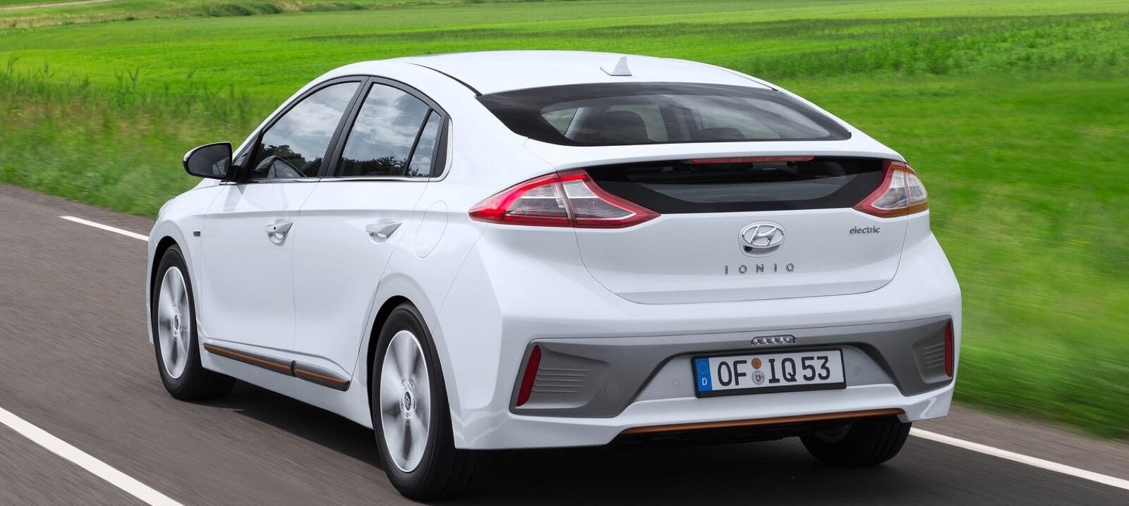 En vit Hyundai Ioniq kör nedför en landsväg. (AI text)