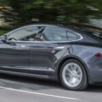 En Tesla Model S kör nedför en landsväg. (AI text)