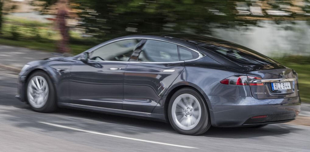 En Tesla Model S kör nedför en landsväg. (AI text)