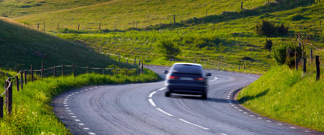En bil kör nedför en snirklig väg. (AI text)
