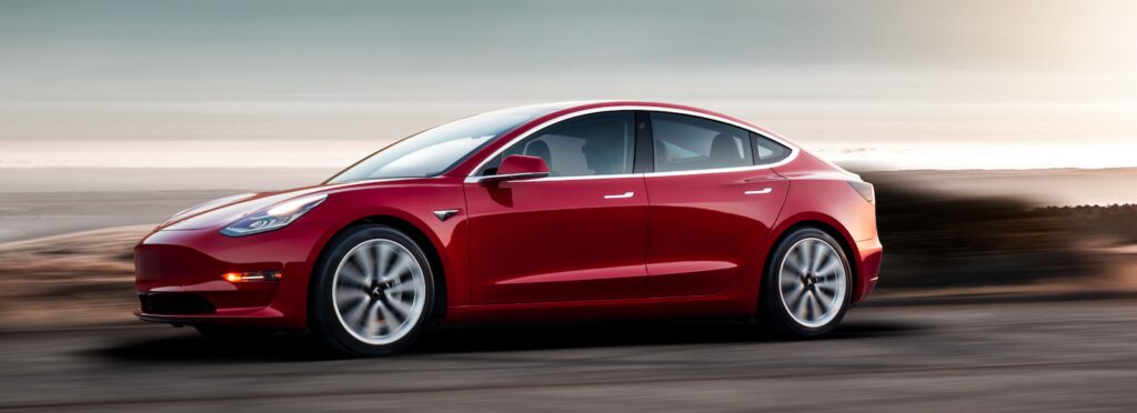 En Tesla Model 3 kör på en väg. (AI text)