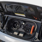 En vit bil med ett plug-in laddstolpe för elbil. (AI text)