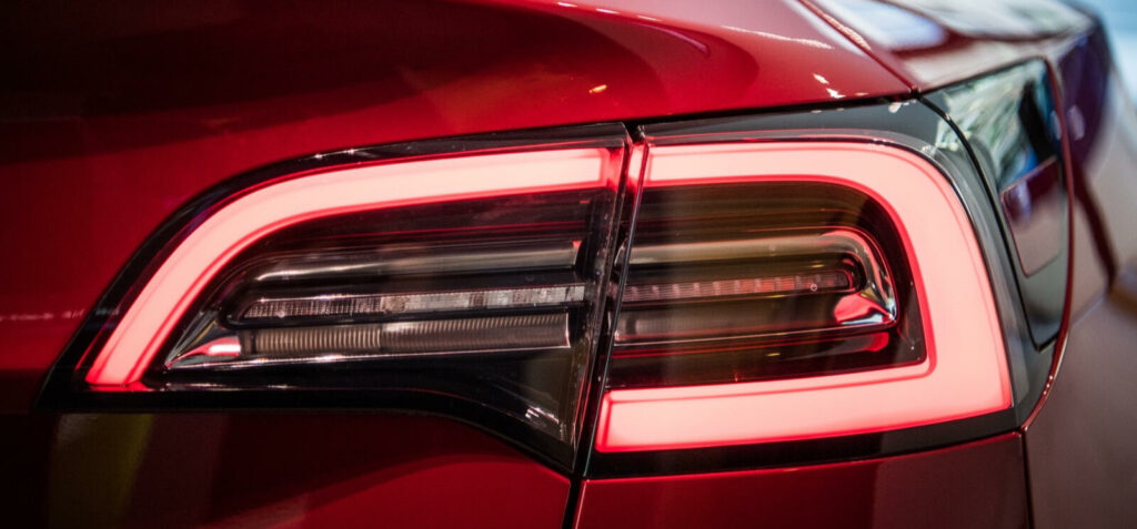 En röd Tesla Model S-bil med rött baklampsskena. (AI text)