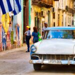 En gata i Havanna med en klassisk bil och folk. (AI text)