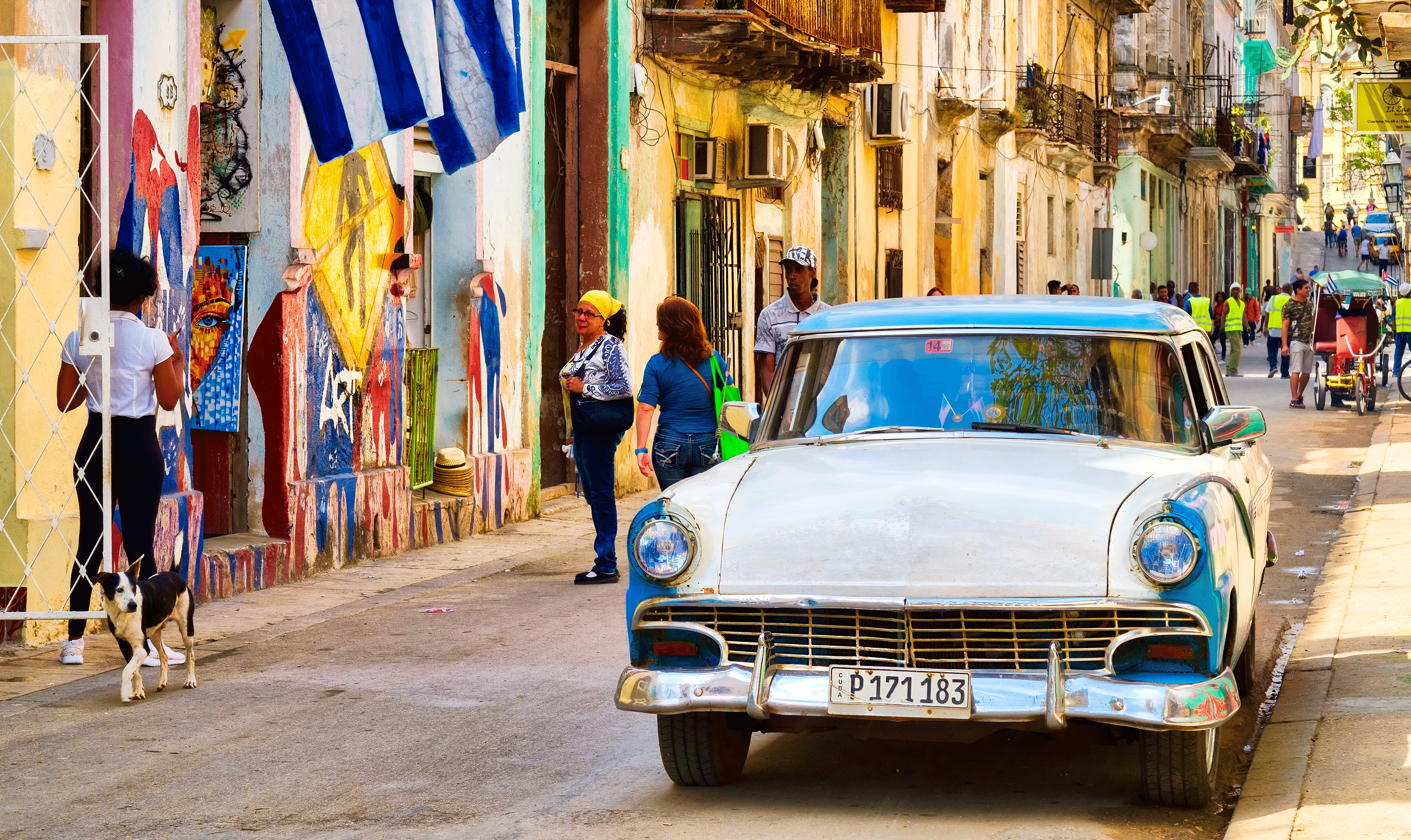 En gata i Havanna med en klassisk bil och folk. (AI text)