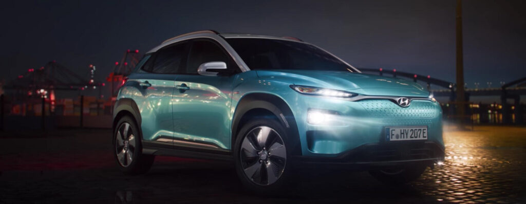 En blå Hyundai EV parkerad framför ett byggnad nattetid. (AI text)