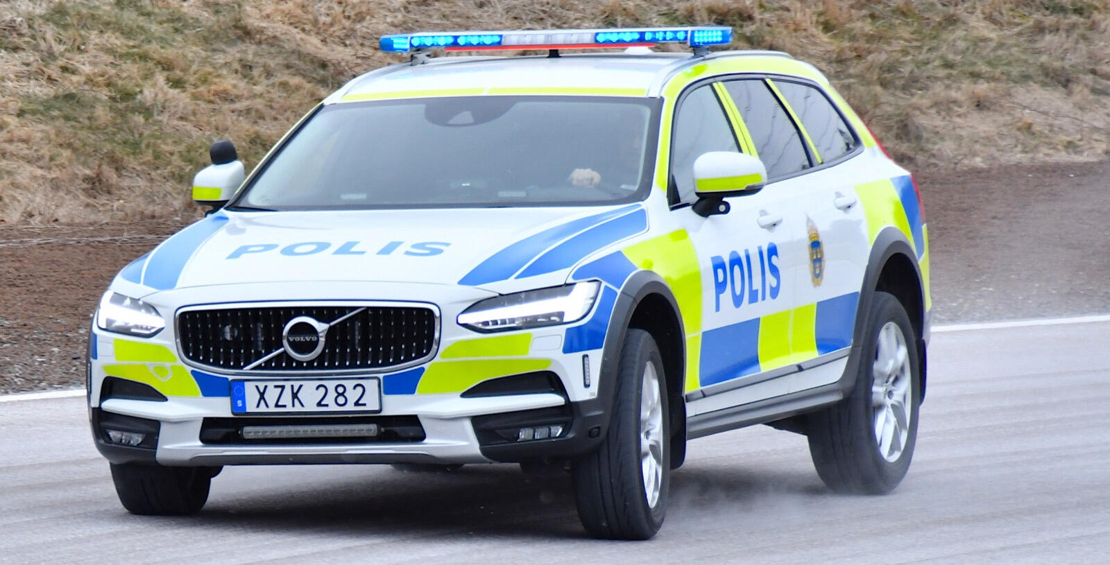 En polisbil kör nedför en bergsväg. (AI text)