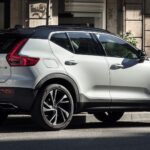 En vit Volvo XC90 SUV parkerad på en stadsgata. (AI text)