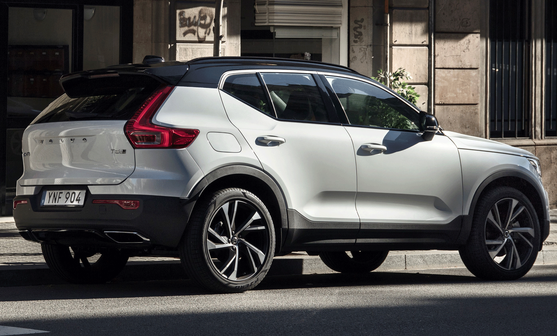 En vit Volvo XC90 SUV parkerad på en stadsgata. (AI text)