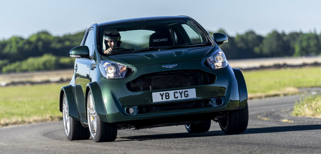 En grön bil kör nerför en landsväg. (AI text)