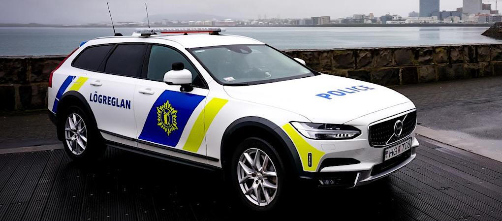 En polisbil står parkerad på gatan framför ett byggnad. (AI text)