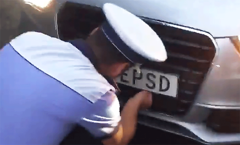 En polisinspektor kontrollerar bilens nummerskylt. (AI text)
