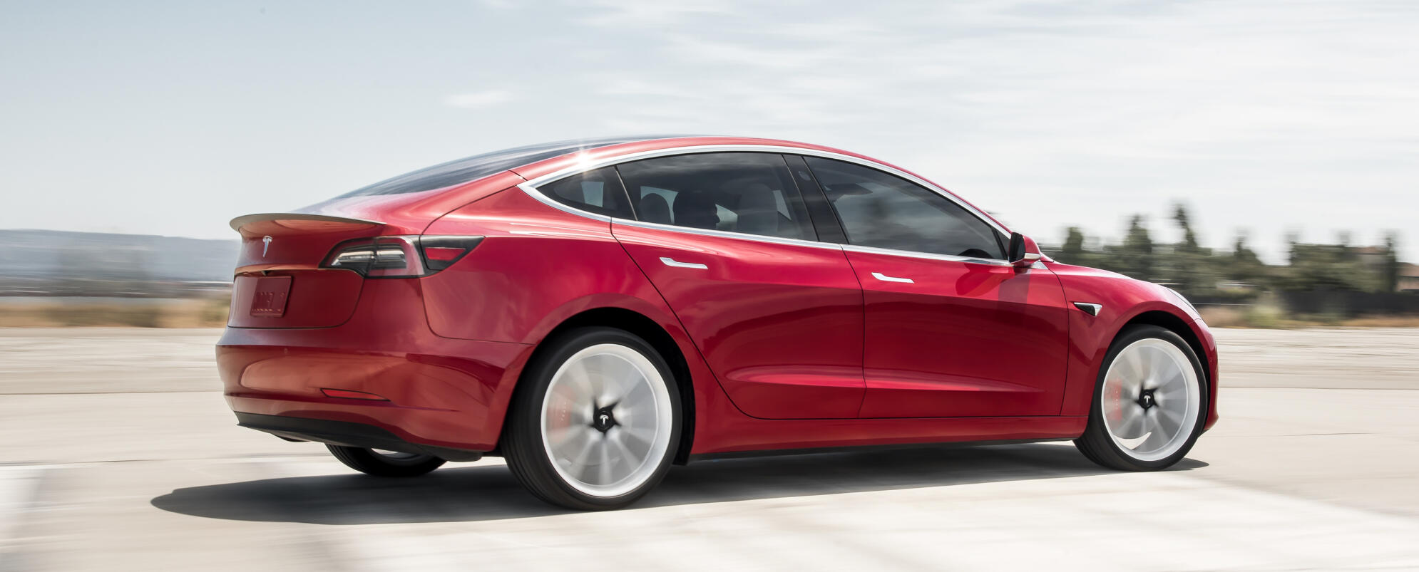 En Tesla Model 3 kör på en väg. (AI text)