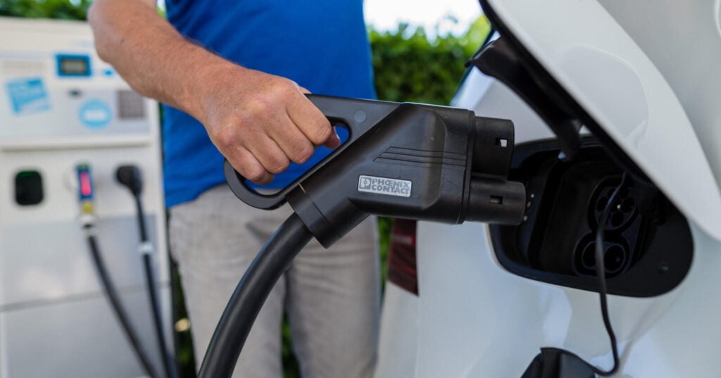 En man fyller på sin elbil vid en bensinstation. (AI text)