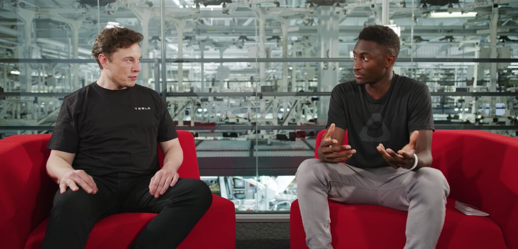 Två män sitter på röda soffor i en fabrik. (AI text)