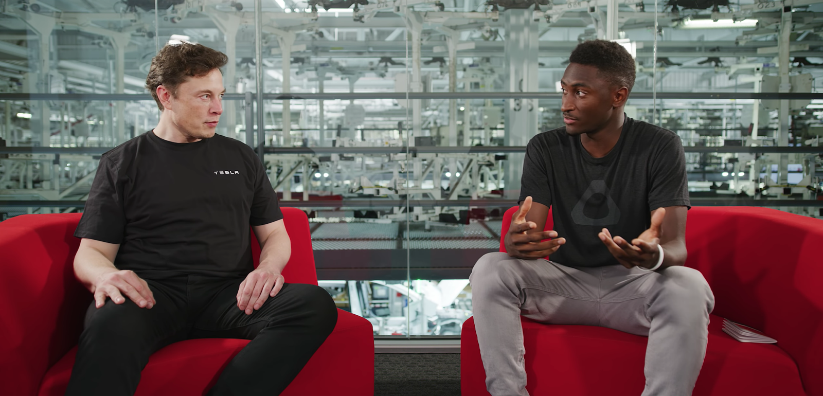 Två män sitter på röda soffor i en fabrik. (AI text)