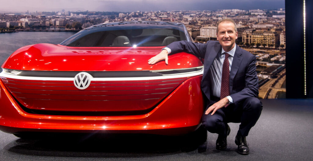 En man i kostym klär sig upp bredvid en Volkswagen e-Tron-konceptbil. (AI text)