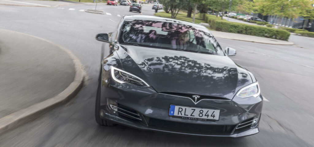 Tesla Model X kör på en stadsgata. (AI text)