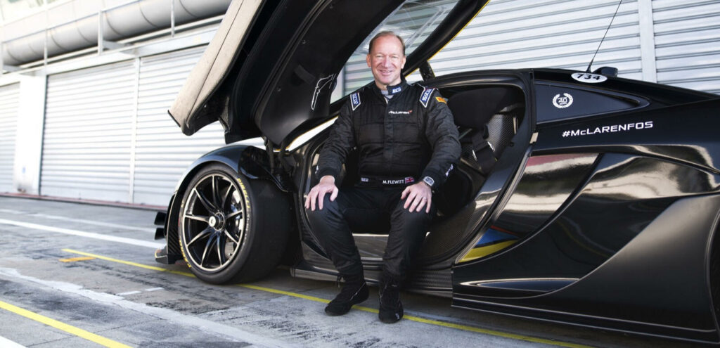 En man sitter framför en svart sportbil. (AI text)