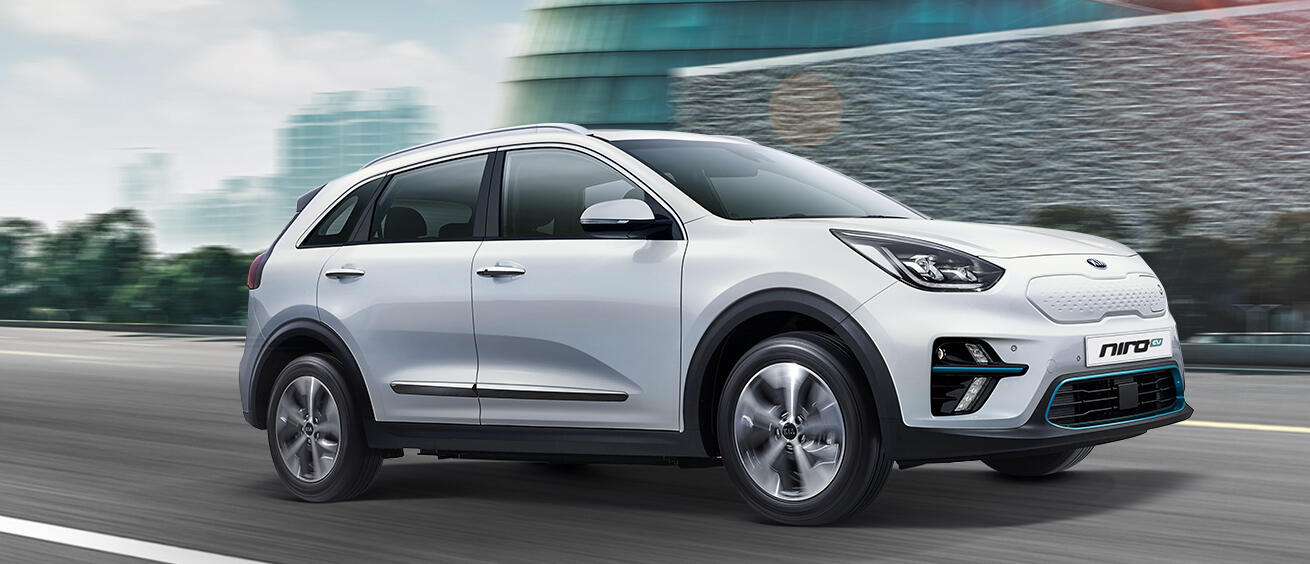 En vit Kia Niro kör nerför en stadsgata. (AI text)