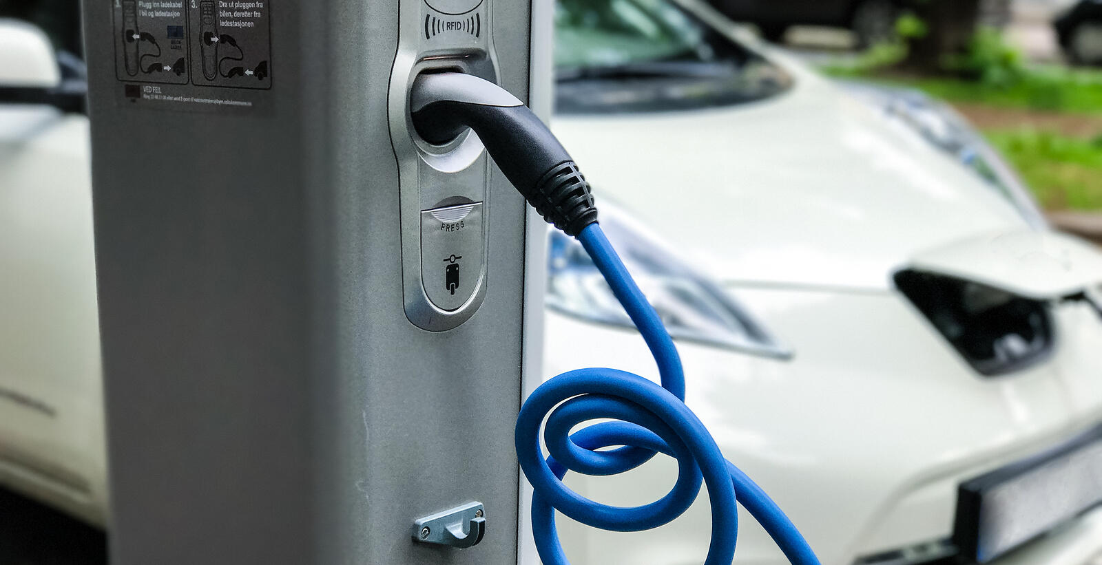 En bil är uppkopplad till en elbilsladdstation. (AI text)