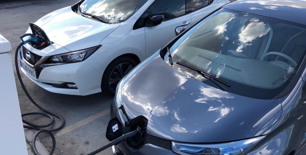 Bilar med eldrift parkerade vid en laddstation (AI text)