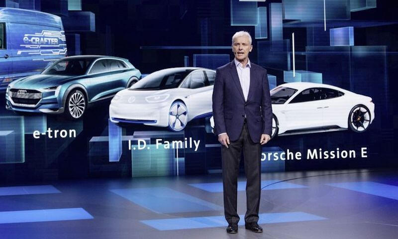 En man står på en scen med en bil framför honom. (AI text)