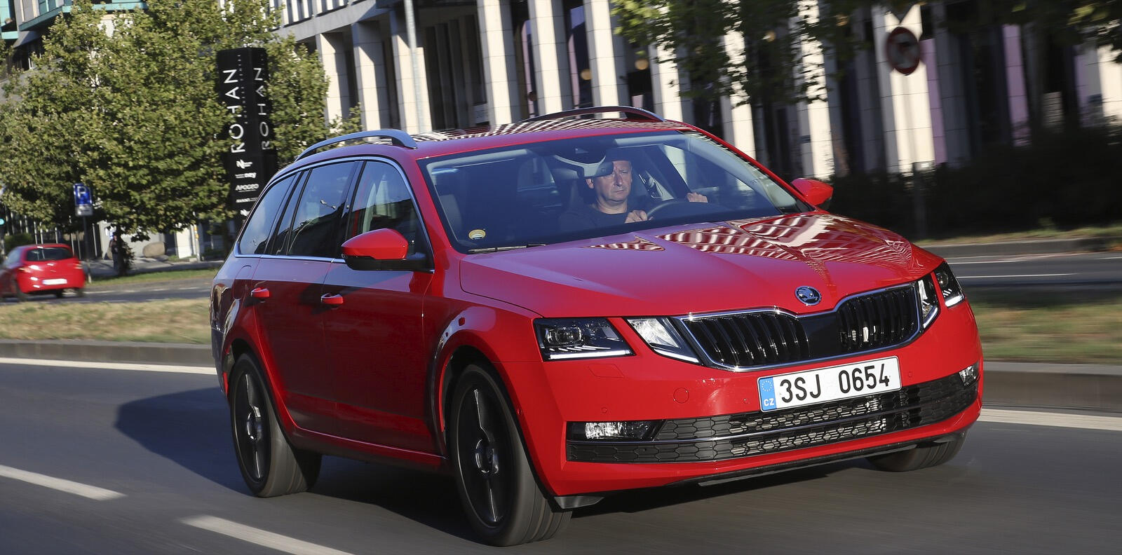 En röd Skoda A3 kör nedför en stadsgata. (AI text)